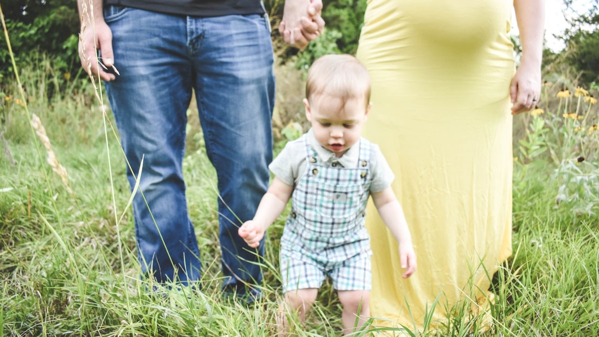 man in black tank top carrying baby in blue and white plaid button up shirt
